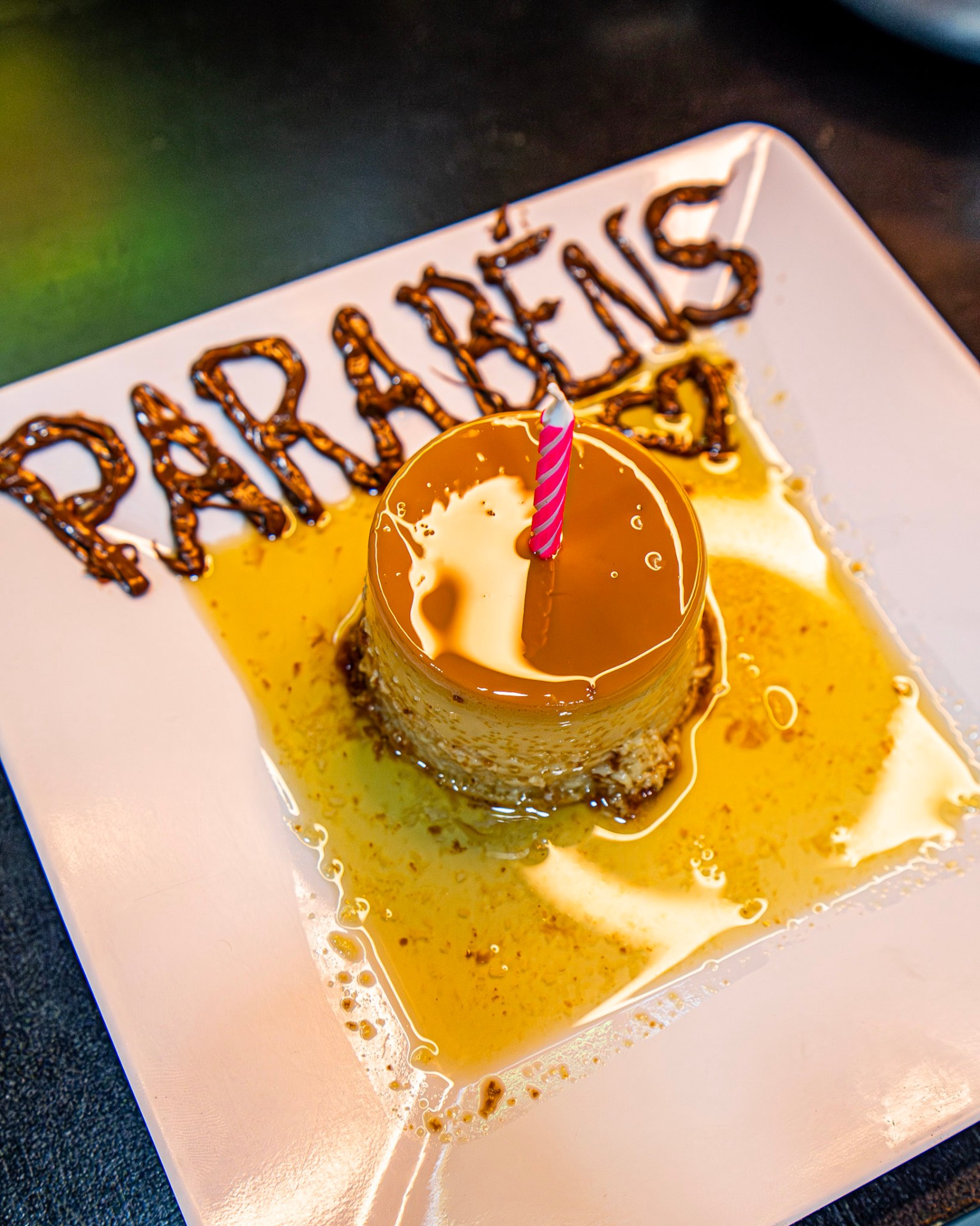 Pudim de leite condensado com vela e Parabéns escrito em calda — promoção aniversariantes do mês Dan's Burger
